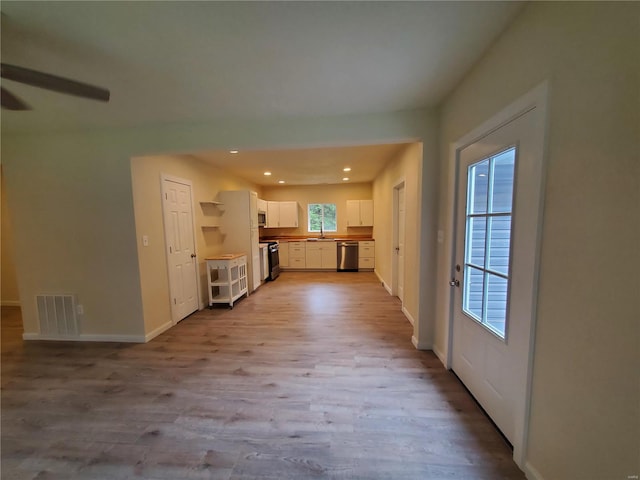 kitchen with a healthy amount of sunlight, light hardwood / wood-style flooring, white cabinets, and appliances with stainless steel finishes