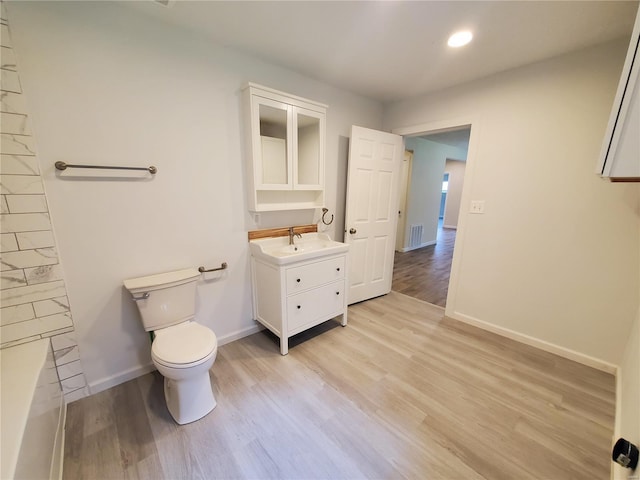 bathroom with wood-type flooring, vanity, and toilet