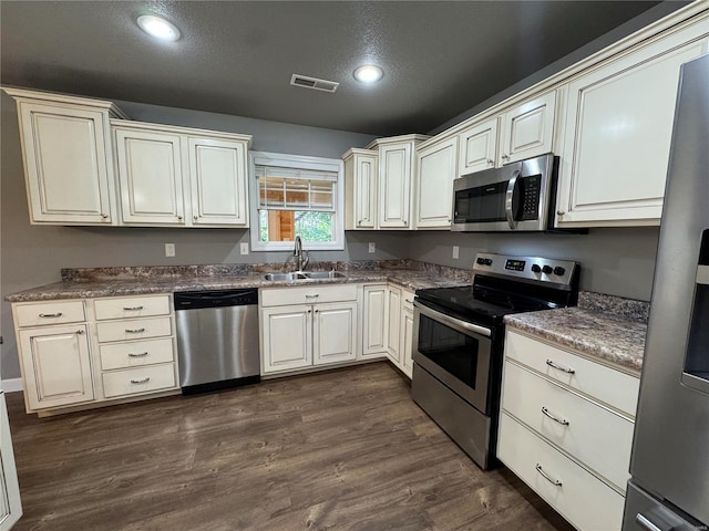 kitchen featuring appliances with stainless steel finishes, sink, dark wood-type flooring, and cream cabinets