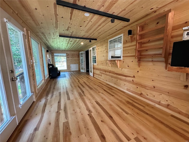 unfurnished living room featuring wood ceiling, wood walls, and light wood-type flooring