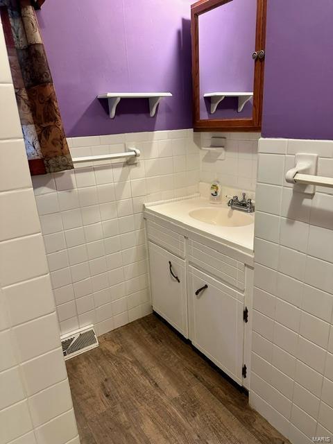 bathroom featuring hardwood / wood-style floors, vanity, and tile walls