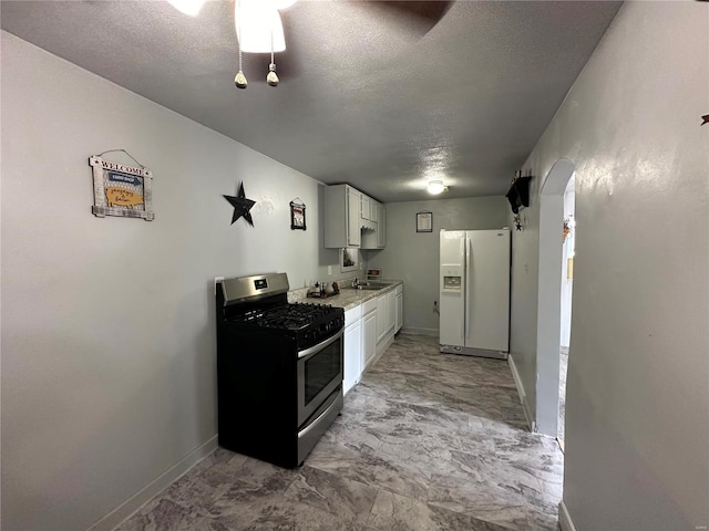 kitchen with white refrigerator with ice dispenser, white cabinets, sink, a textured ceiling, and gas stove