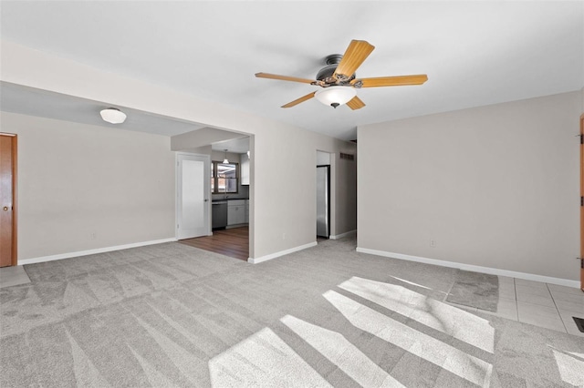 spare room featuring baseboards, ceiling fan, and light colored carpet