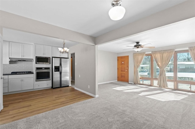 kitchen with white cabinets, stainless steel appliances, and light colored carpet