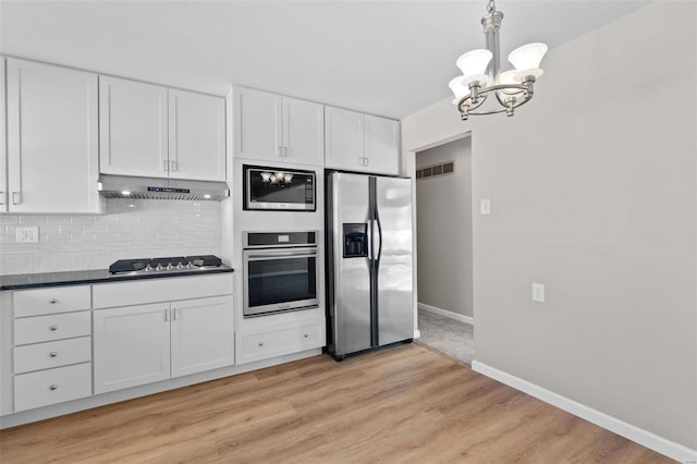 kitchen with stainless steel appliances, dark countertops, visible vents, white cabinets, and under cabinet range hood