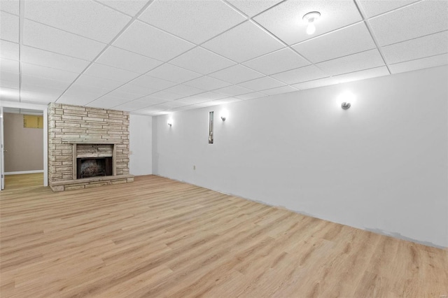 finished basement with a paneled ceiling, a fireplace, and light wood finished floors