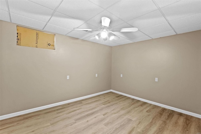 empty room with baseboards, a ceiling fan, a drop ceiling, and wood finished floors