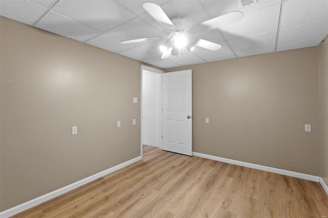 spare room with light wood-style floors, a ceiling fan, baseboards, and a drop ceiling