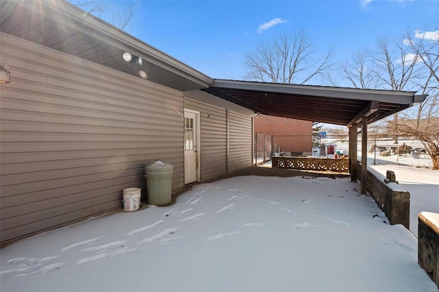 snow covered patio featuring a carport