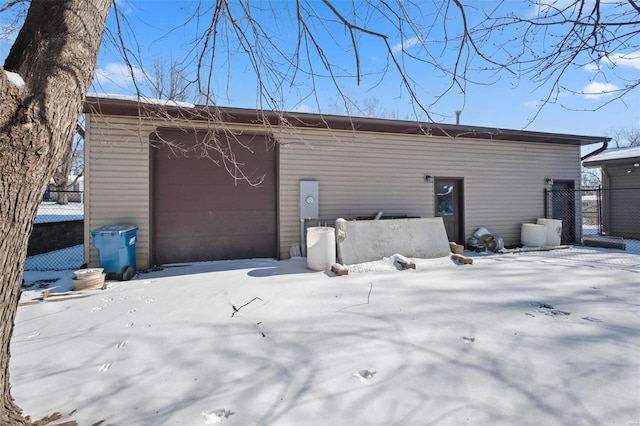 snow covered garage featuring fence