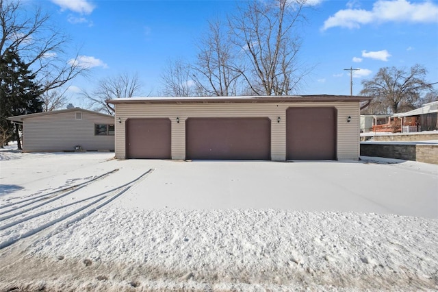 snow covered garage featuring a detached garage