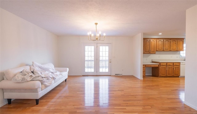 living room with a textured ceiling, light wood-type flooring, and a notable chandelier