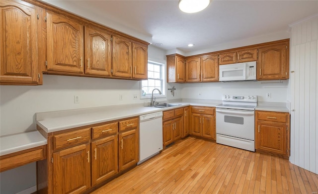 kitchen with white appliances, light wood-type flooring, and sink