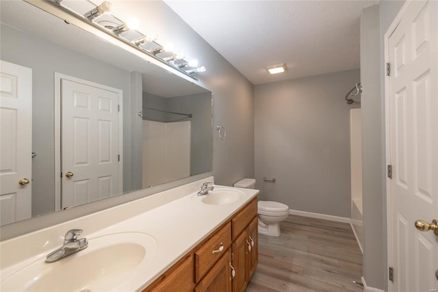 full bathroom featuring a textured ceiling, bathing tub / shower combination, hardwood / wood-style floors, toilet, and vanity