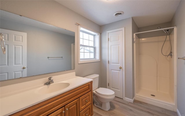 bathroom featuring vanity, wood-type flooring, walk in shower, and toilet