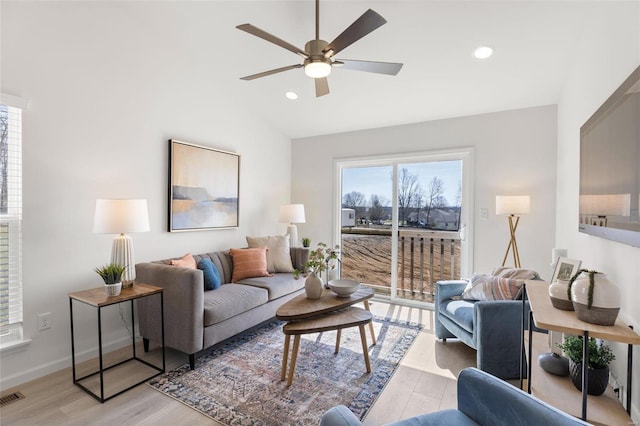 living room with lofted ceiling, ceiling fan, and light wood-type flooring