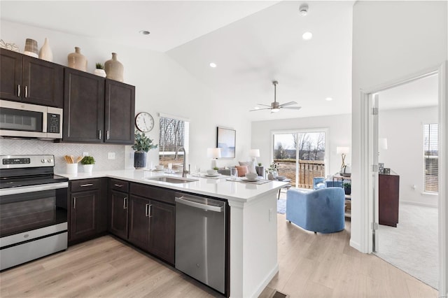 kitchen featuring ceiling fan, sink, stainless steel appliances, kitchen peninsula, and light wood-type flooring