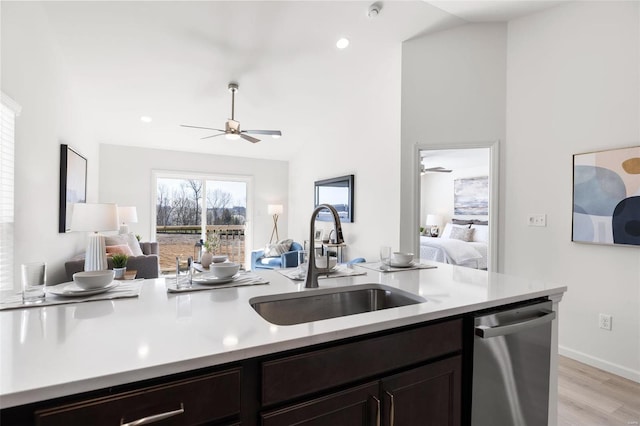 kitchen with stainless steel dishwasher, dark brown cabinetry, vaulted ceiling, sink, and light hardwood / wood-style floors