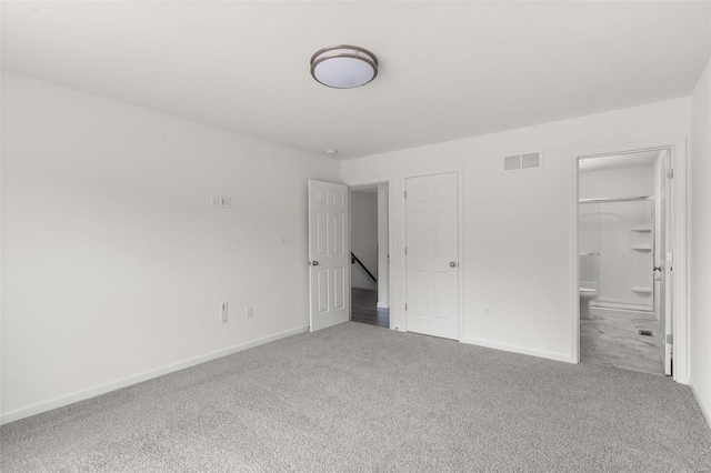 unfurnished bedroom featuring ensuite bath and carpet floors