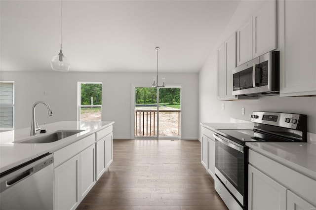 kitchen featuring appliances with stainless steel finishes, pendant lighting, dark hardwood / wood-style floors, sink, and white cabinetry