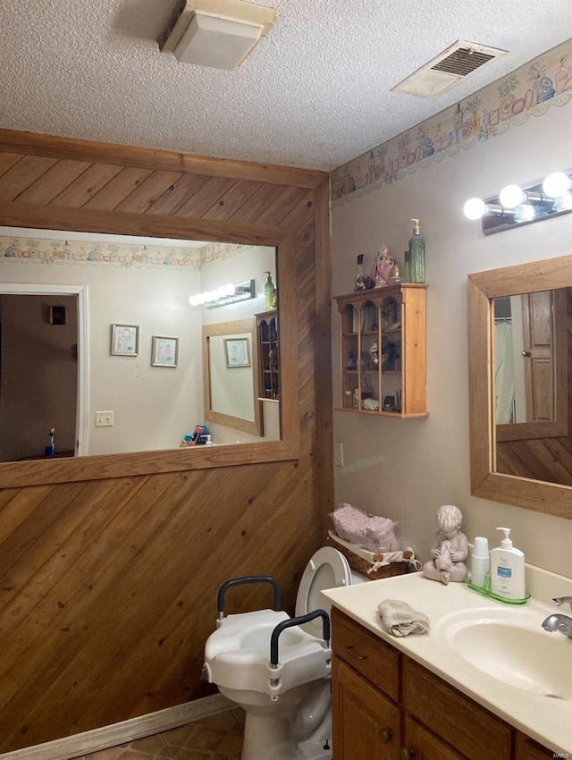 bathroom featuring wooden walls, tile flooring, a textured ceiling, and large vanity