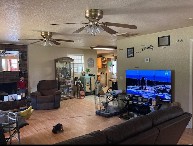 living room with brick wall, ceiling fan, hardwood / wood-style flooring, and a textured ceiling