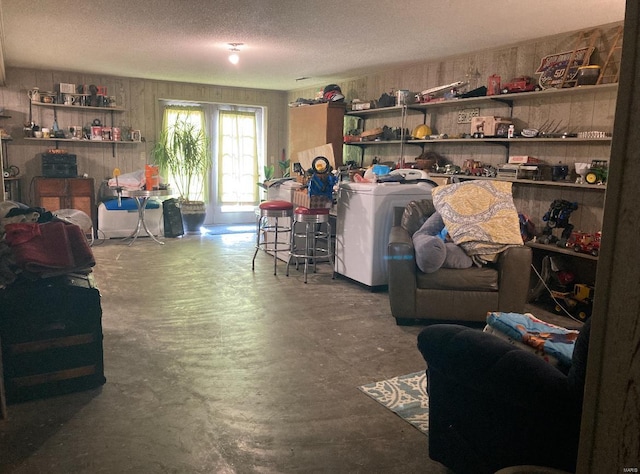 living room featuring concrete flooring, a textured ceiling, and washer / dryer