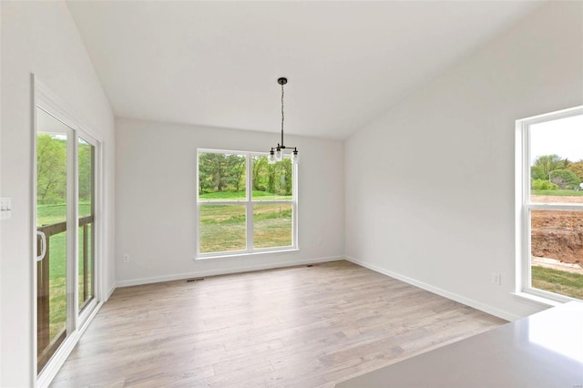 unfurnished dining area featuring lofted ceiling and plenty of natural light