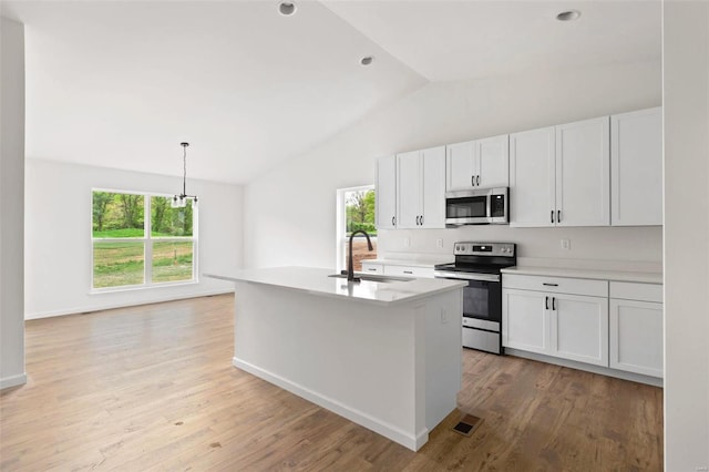 kitchen with white cabinets, a center island with sink, stainless steel appliances, pendant lighting, and sink