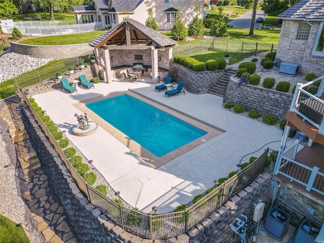 view of pool featuring an outdoor stone fireplace, a gazebo, a patio, a lawn, and cooling unit