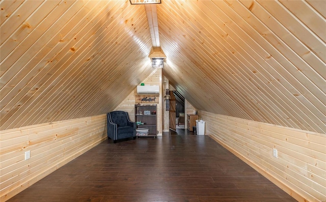 additional living space featuring dark hardwood / wood-style floors, lofted ceiling, wooden walls, and an AC wall unit