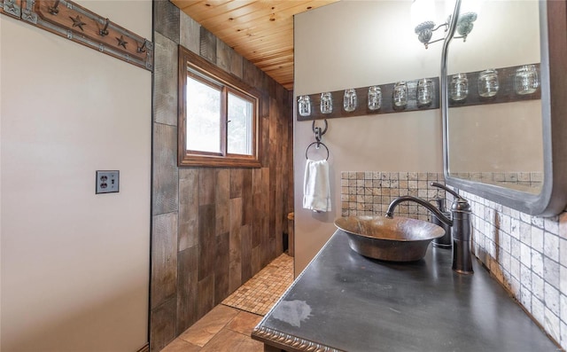 bathroom with wooden ceiling, sink, and a tile shower