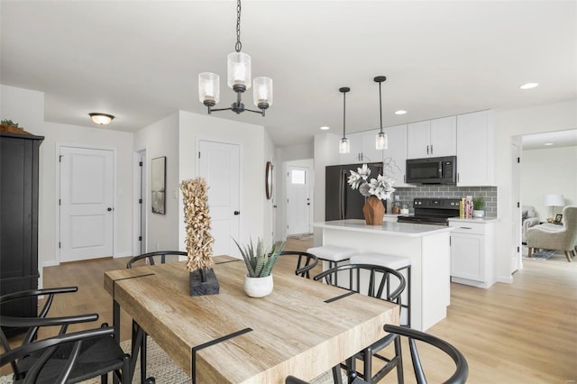 dining area featuring light wood-type flooring and a notable chandelier