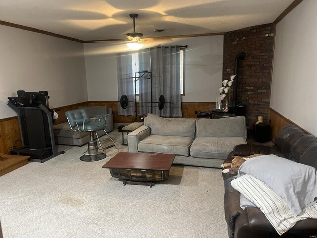 living room with crown molding, carpet floors, ceiling fan, and a wood stove