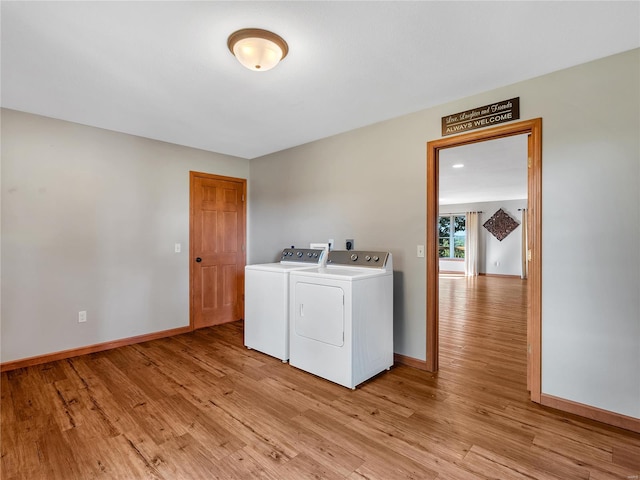 washroom with washing machine and clothes dryer and light hardwood / wood-style floors