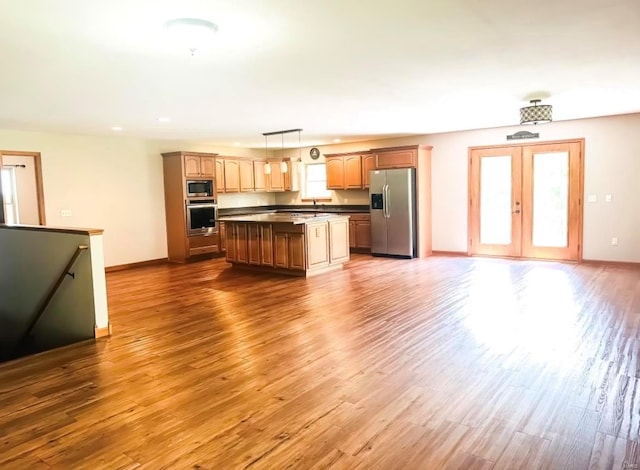 kitchen featuring appliances with stainless steel finishes, sink, a kitchen island, hardwood / wood-style flooring, and hanging light fixtures