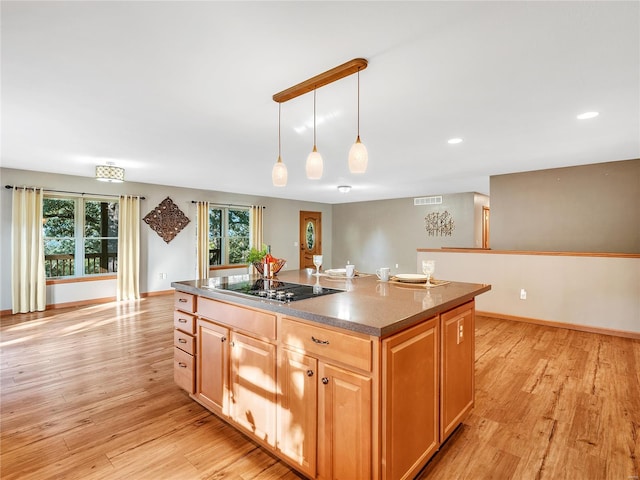 kitchen with light wood-type flooring, black electric stovetop, pendant lighting, and a kitchen island