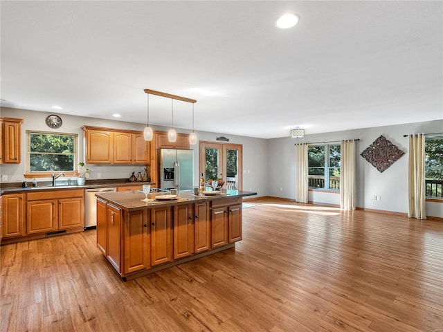 kitchen featuring light wood-type flooring, stainless steel appliances, plenty of natural light, and a kitchen island