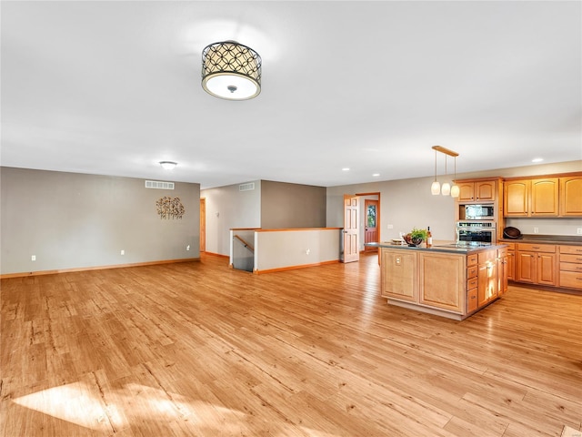 kitchen featuring light wood-type flooring, a center island, stainless steel appliances, and hanging light fixtures