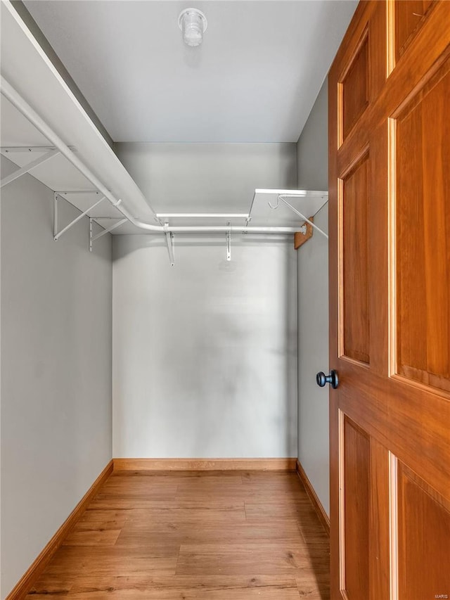 walk in closet with light hardwood / wood-style floors