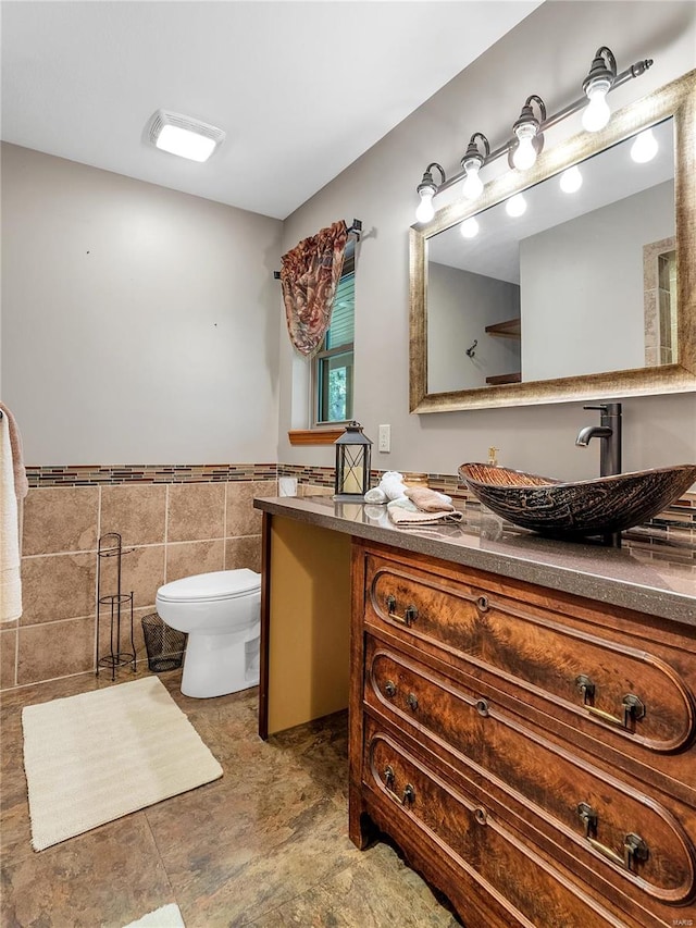 bathroom with tile patterned flooring, tile walls, toilet, and vanity