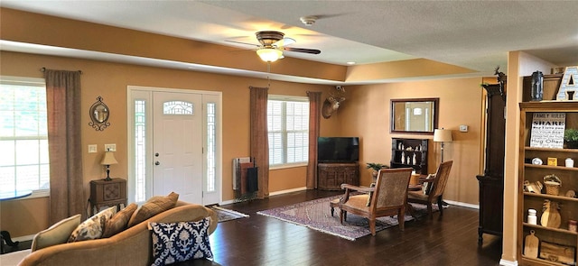 foyer with dark wood-type flooring, a textured ceiling, ceiling fan, and a raised ceiling