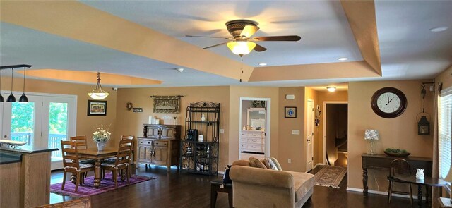 living room featuring dark hardwood / wood-style floors, ceiling fan, and a raised ceiling