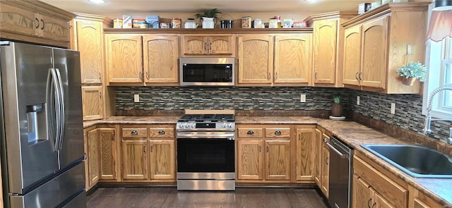 kitchen with appliances with stainless steel finishes, tasteful backsplash, sink, and dark wood-type flooring