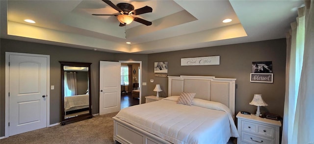 carpeted bedroom featuring ceiling fan and a tray ceiling