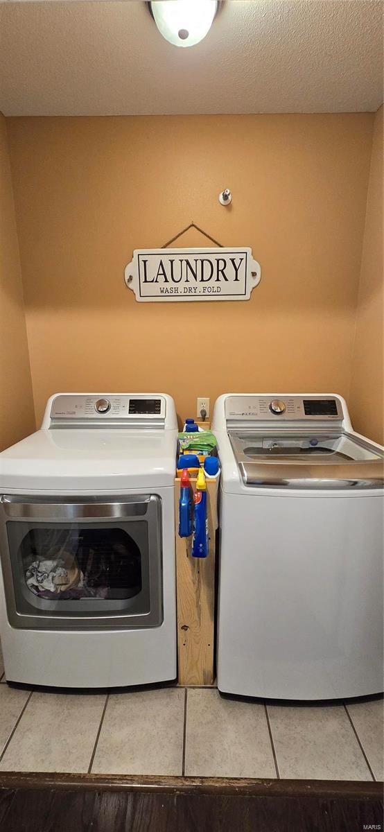 laundry area with tile patterned flooring, washer and clothes dryer, and a textured ceiling