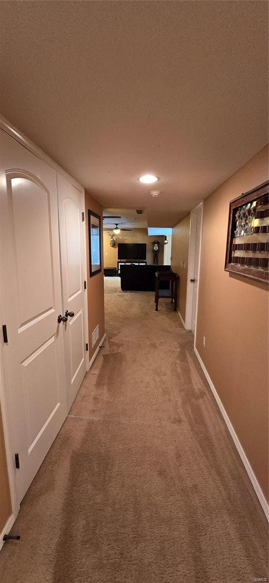 hall featuring a textured ceiling and carpet flooring