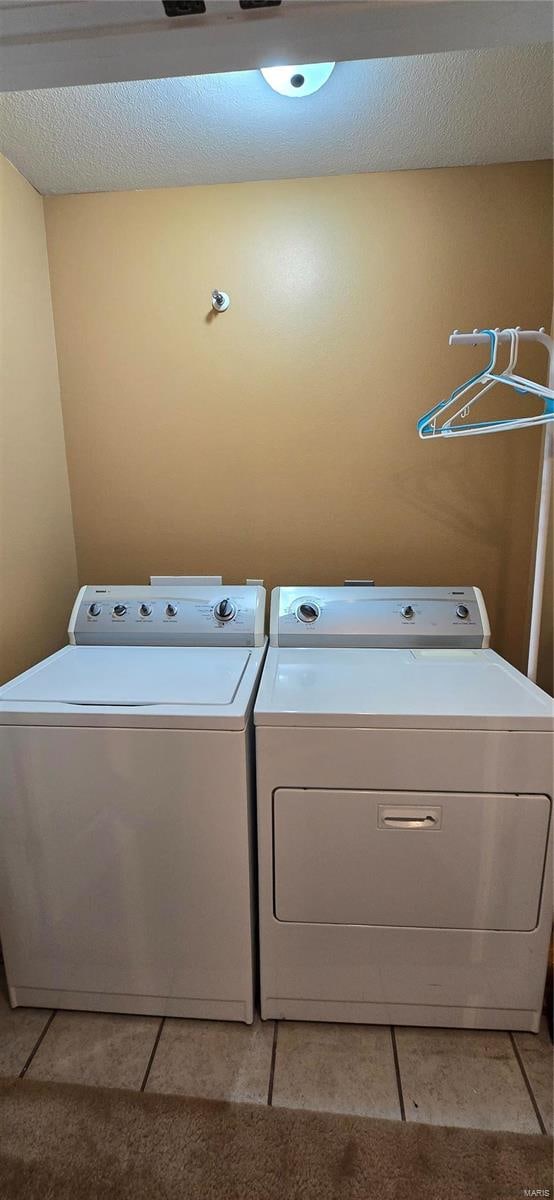 laundry area with light tile patterned flooring, separate washer and dryer, and a textured ceiling