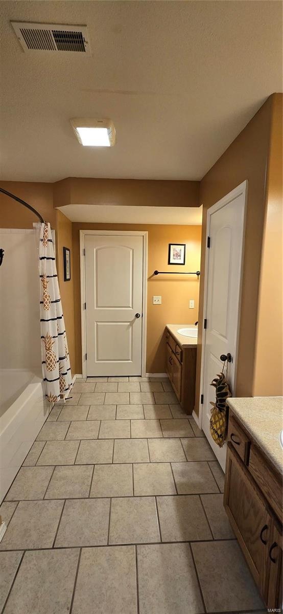 bathroom featuring shower / tub combo, tile patterned flooring, vanity, and a textured ceiling