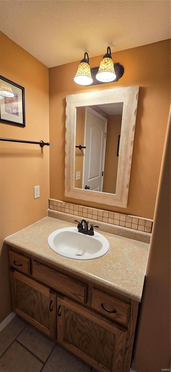 bathroom with vanity, a textured ceiling, and tile patterned flooring